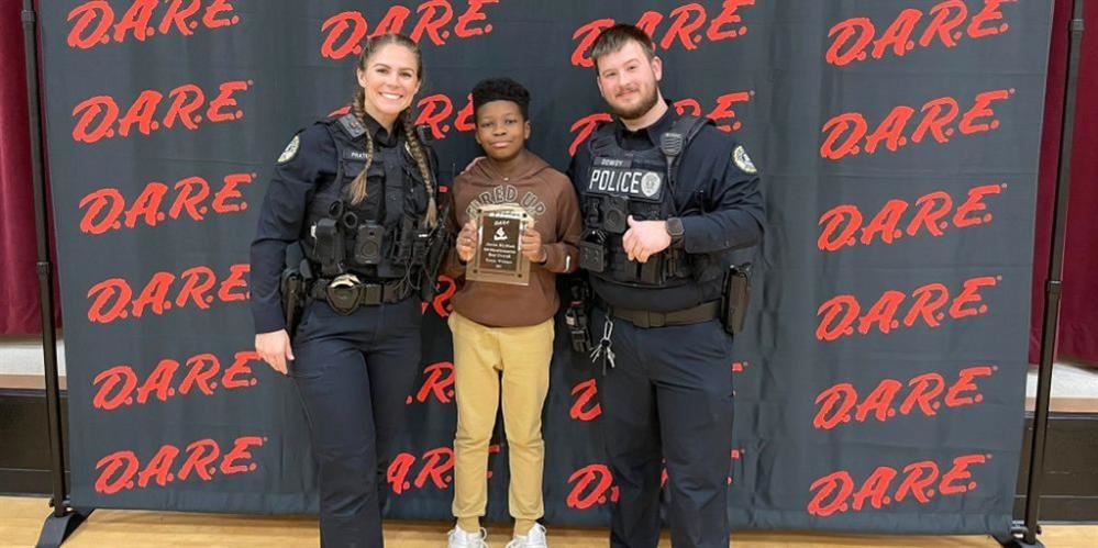  Police Officer standing with the student that won the overall D.A.R.E. award
